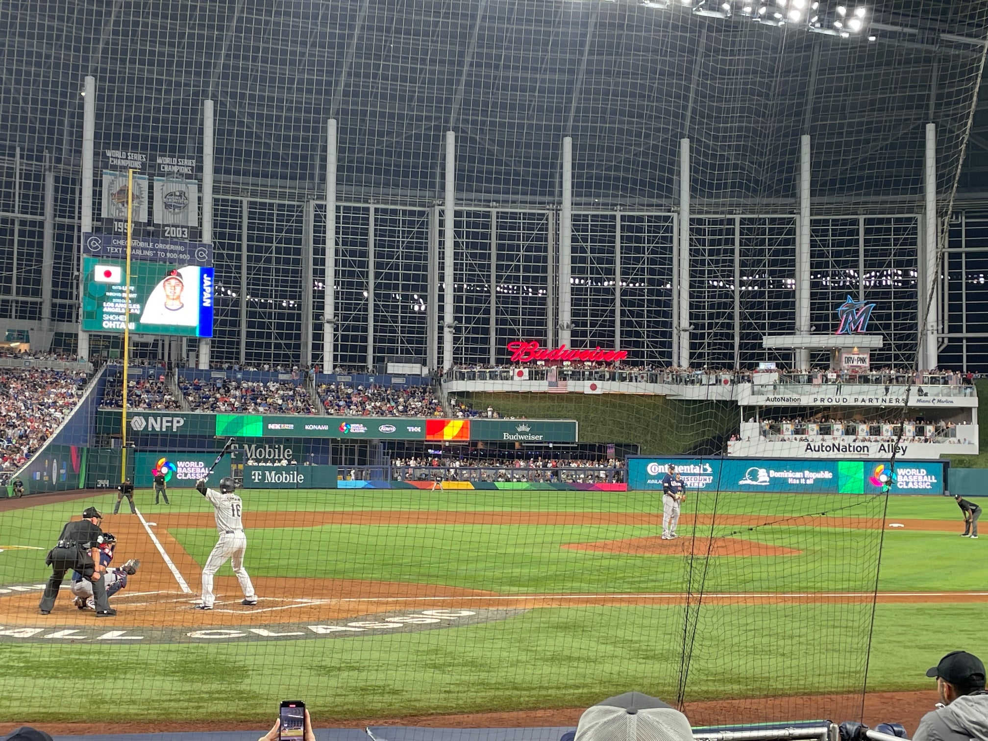 Shohei Ohtani batting during the World Baseball Classic game between Japan and the USA, with fans in the background and stadium branding visible.